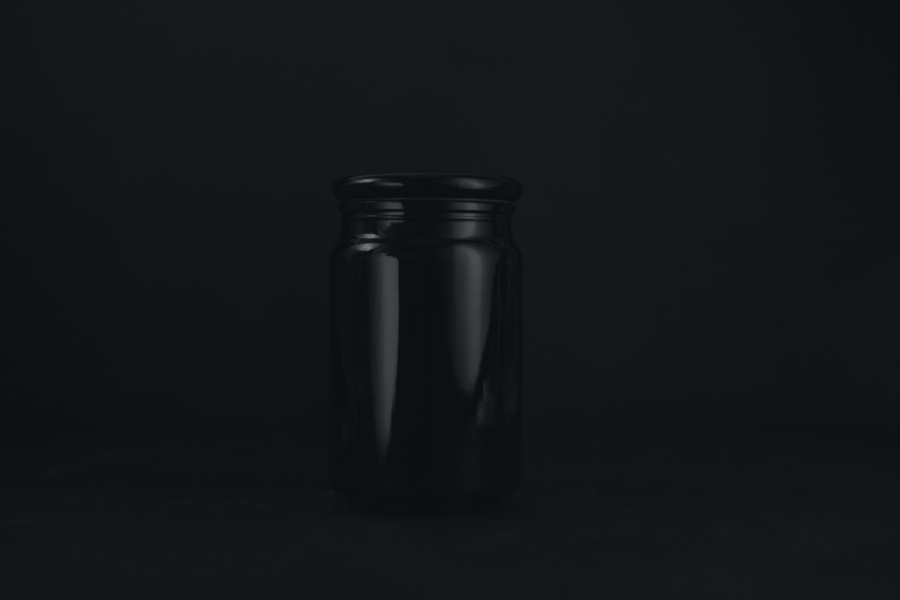 Een elegante zwarte glanzende fles met ronde dop op een zwarte achtergrond