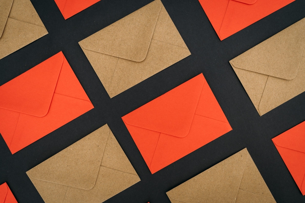 Een herhalend patroon van oranje en bruine enveloppen diagonaal gerangschikt op een donkere achtergrond