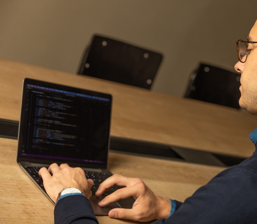De founder van Heave Webdesign Antwerpen, Maarten, die geconcentreerd aan het programmeren is op een laptop met code op het scherm