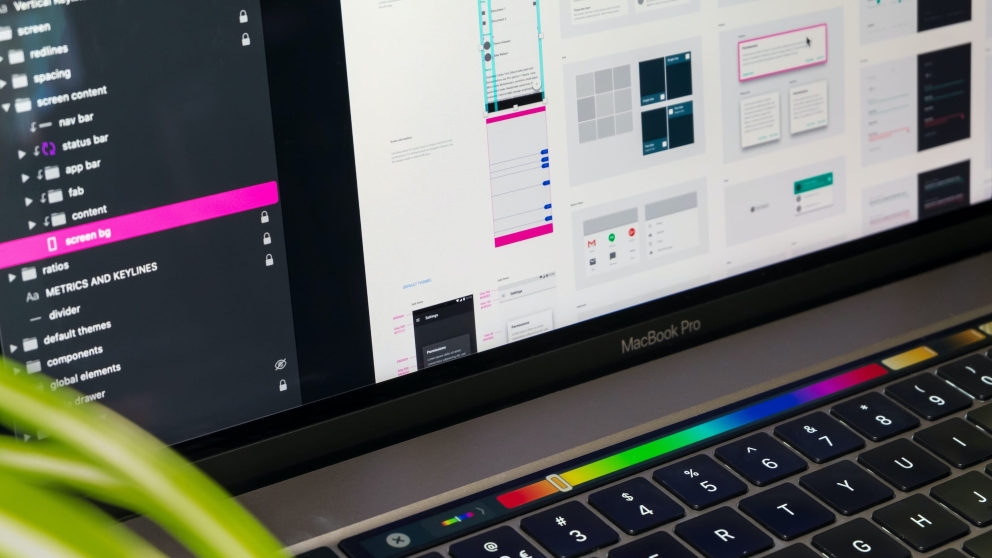 Een close-up van een MacBook Pro laptop met een UI design applicatie open, toont verschillende interface elementen en een Touch Bar met kleurgradi&euml;nt