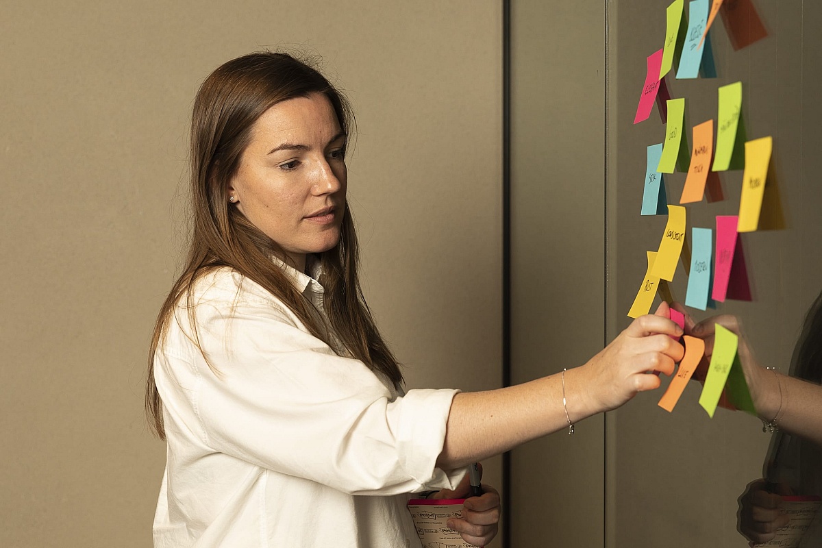A web designer at Heave web design studio Antwerp organizes her thoughts on a project using a colorful series of sticky bills on a wall as part of the design component of the web design process.